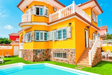 uma casa amarela grande e bonita com piscina e jardim