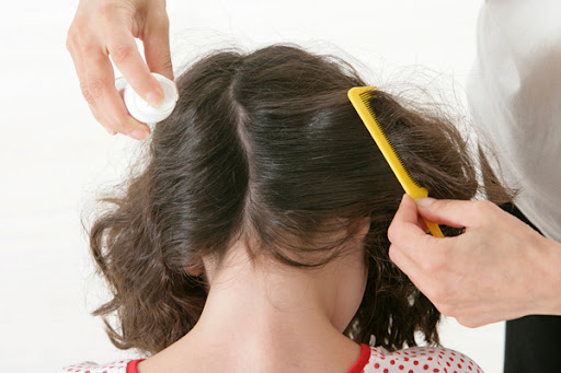 mulher penteando o cabelo de menina piolhenta