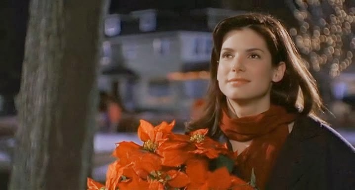Sandra Bullock em uma cena do filme Enquanto voce dormia segurando flores na mão