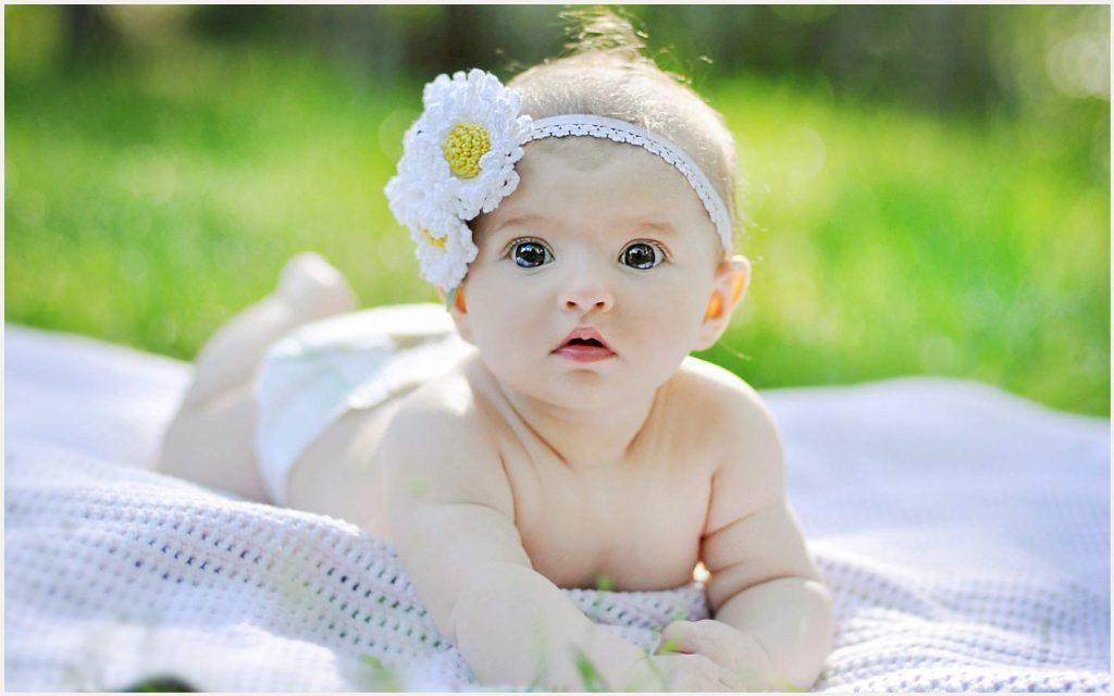 menina bebe pequena com uma flor na cabeça