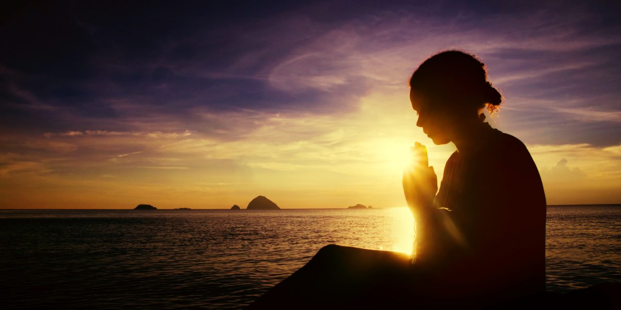 mulher orando sob o nascer do sol