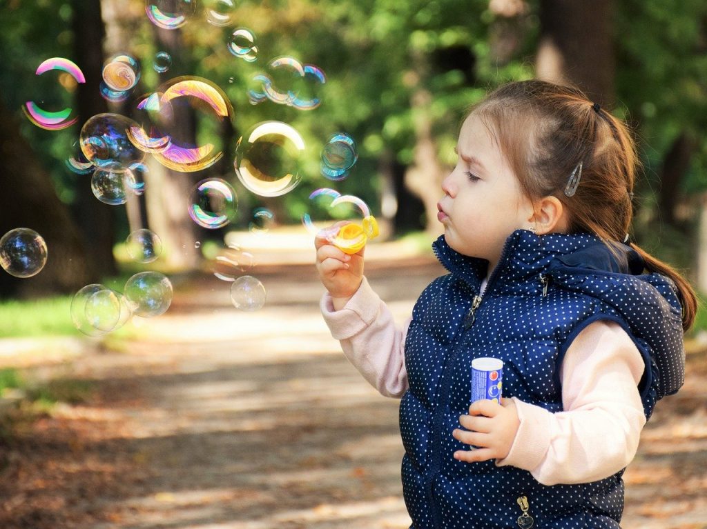 criança menina fazendo bolhas de sabão