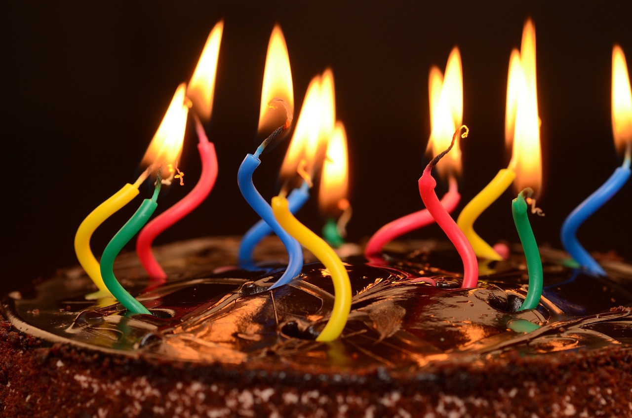 bolo de aniversário com velas coloridas e tortas