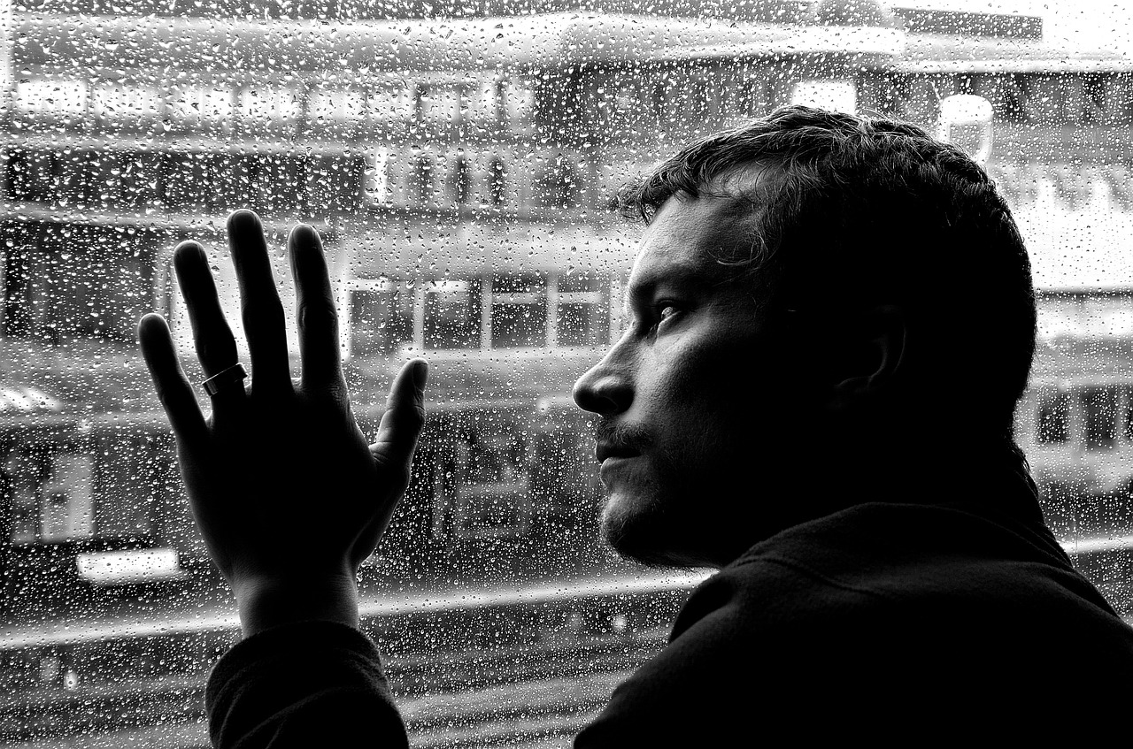 homem triste e depressivo na janela de sua casa