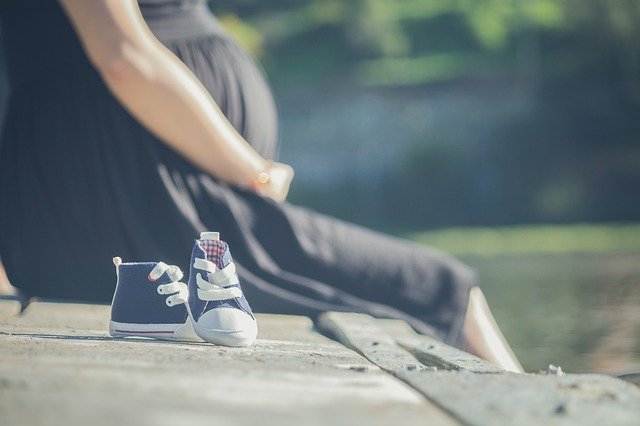 mulher grávida sentada e sapatinhos de bebê