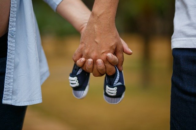casal segurando os sapatos de um bebê