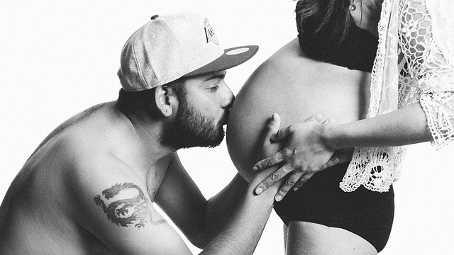 homem beijando a barriga de uma mulher grávida