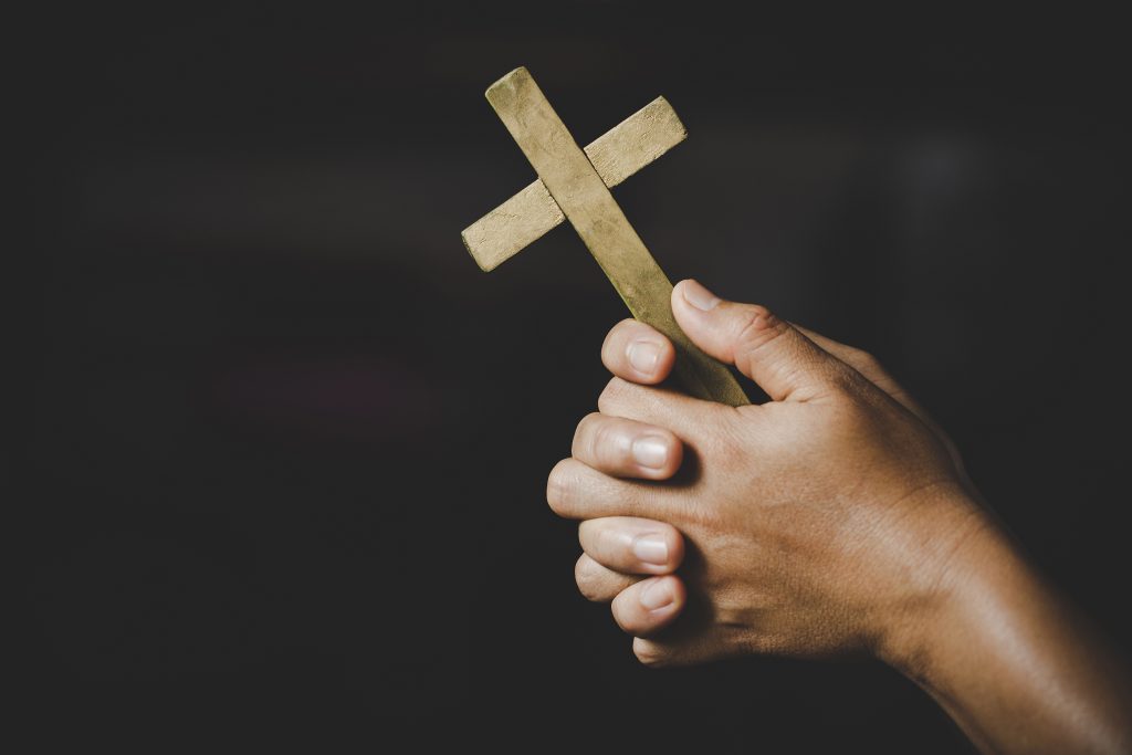 mão segurando cruz