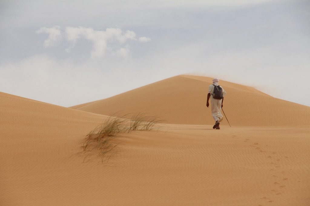homem andando na areia do deserto